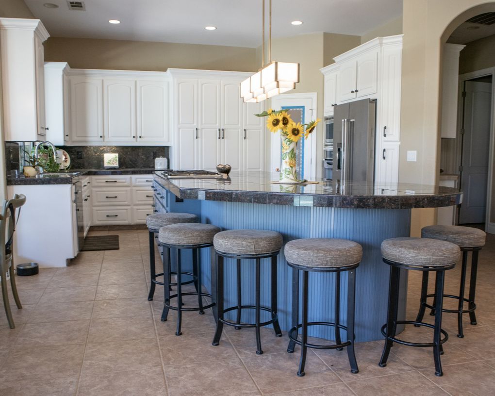 A kitchen with a blue island and stools