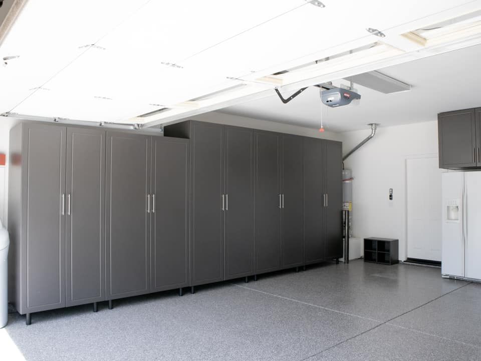 A garage with a lot of cabinets and a garage door open.