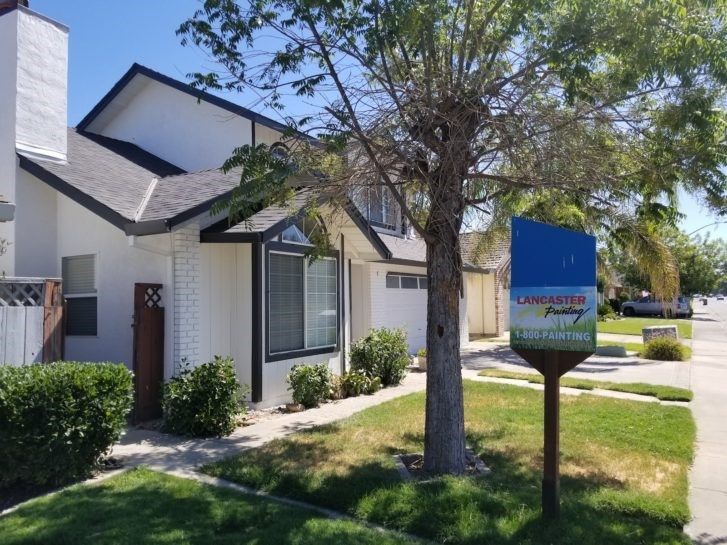 A white house with a blue sign in front of it