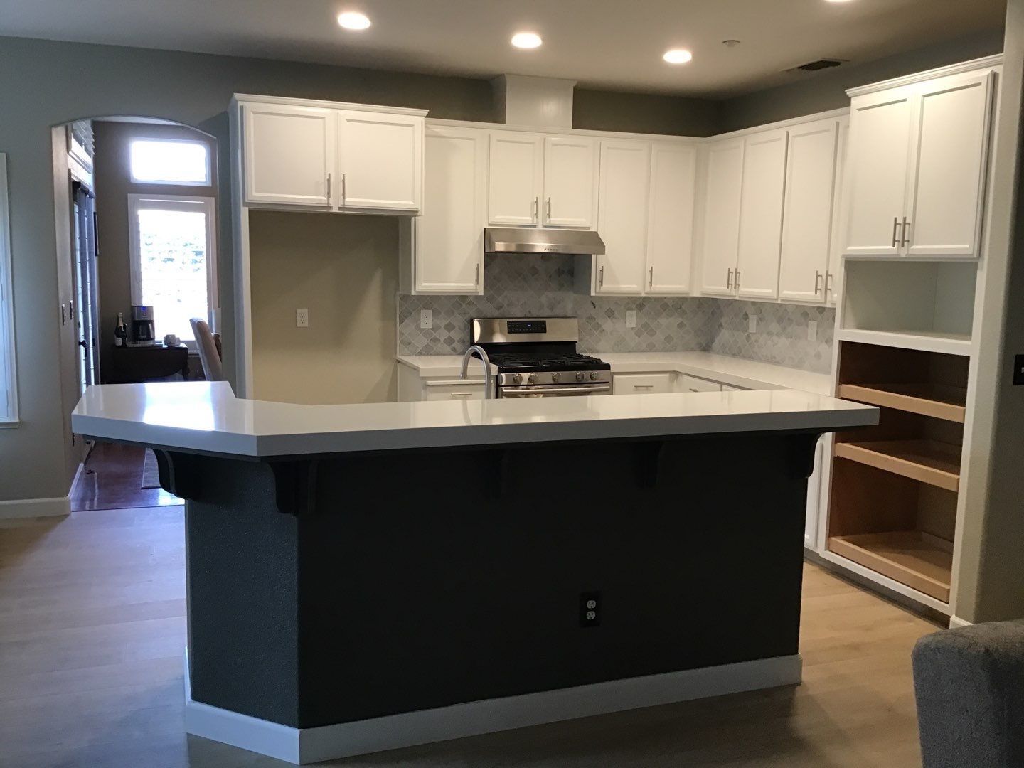 A kitchen with white cabinets and a stove top oven