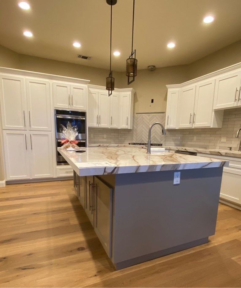 A kitchen with white cabinets and a large island in the middle.