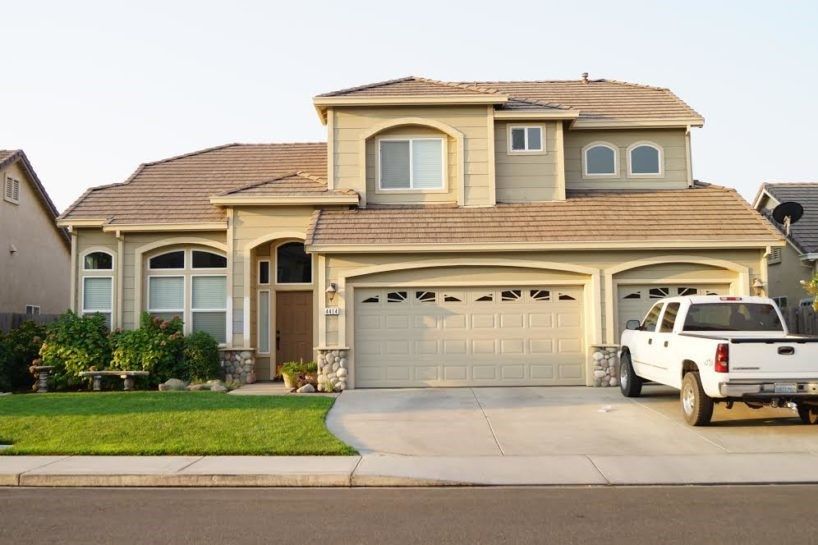 A white truck is parked in front of a large house