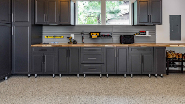 A kitchen with gray cabinets and a wooden counter top.