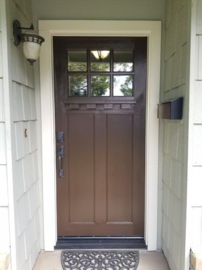 A brown door with a white trim is sitting on a porch.