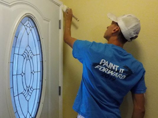 A man wearing a blue shirt that says paint it forward
