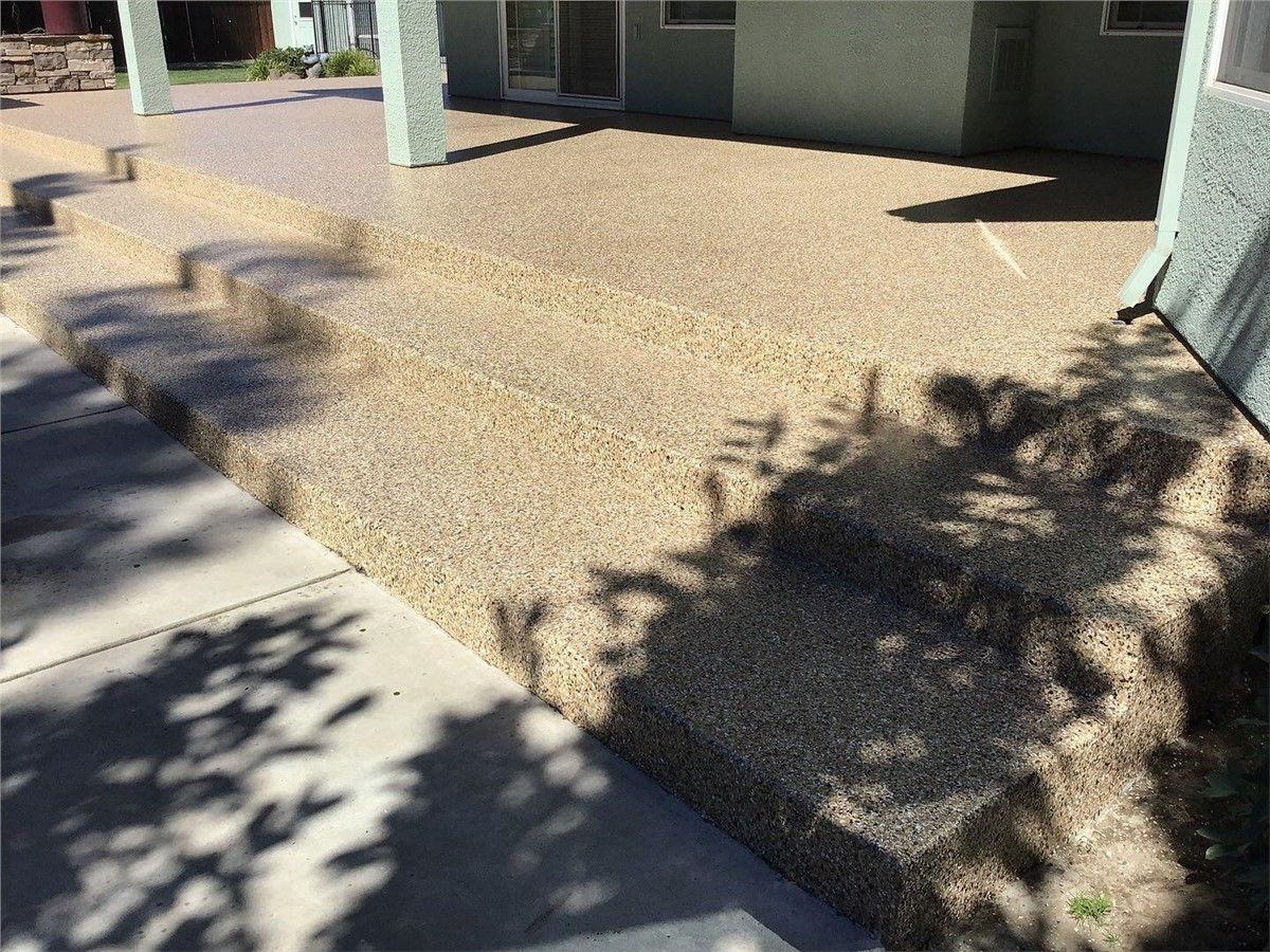 There is a shadow of a tree on the sidewalk in front of a house.