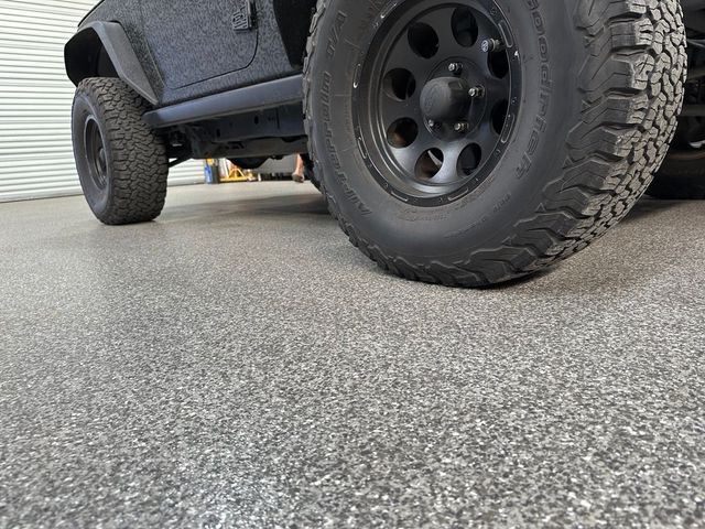 A black jeep is parked on a garage floor.
