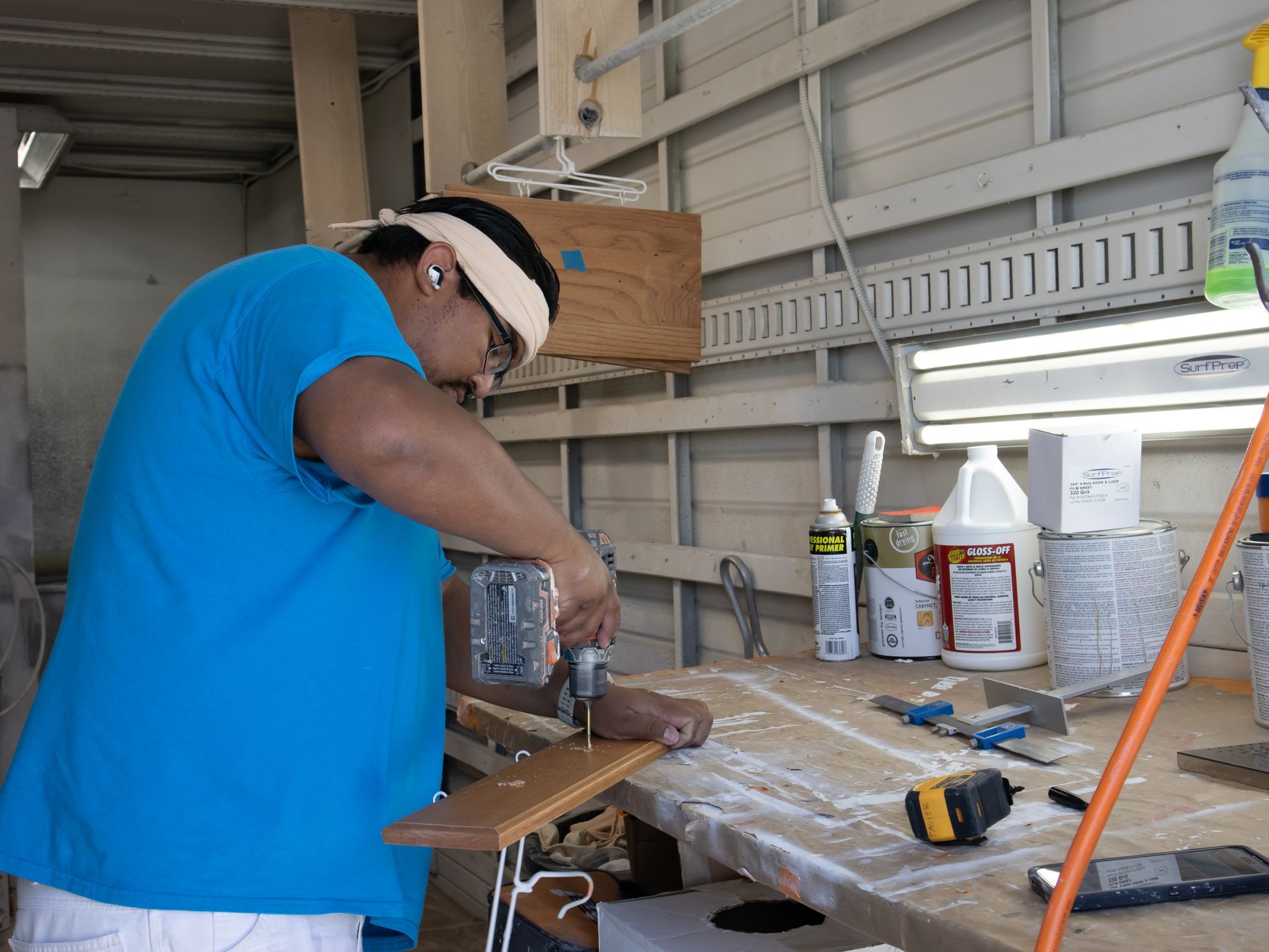 A man in a blue shirt is working on a piece of wood