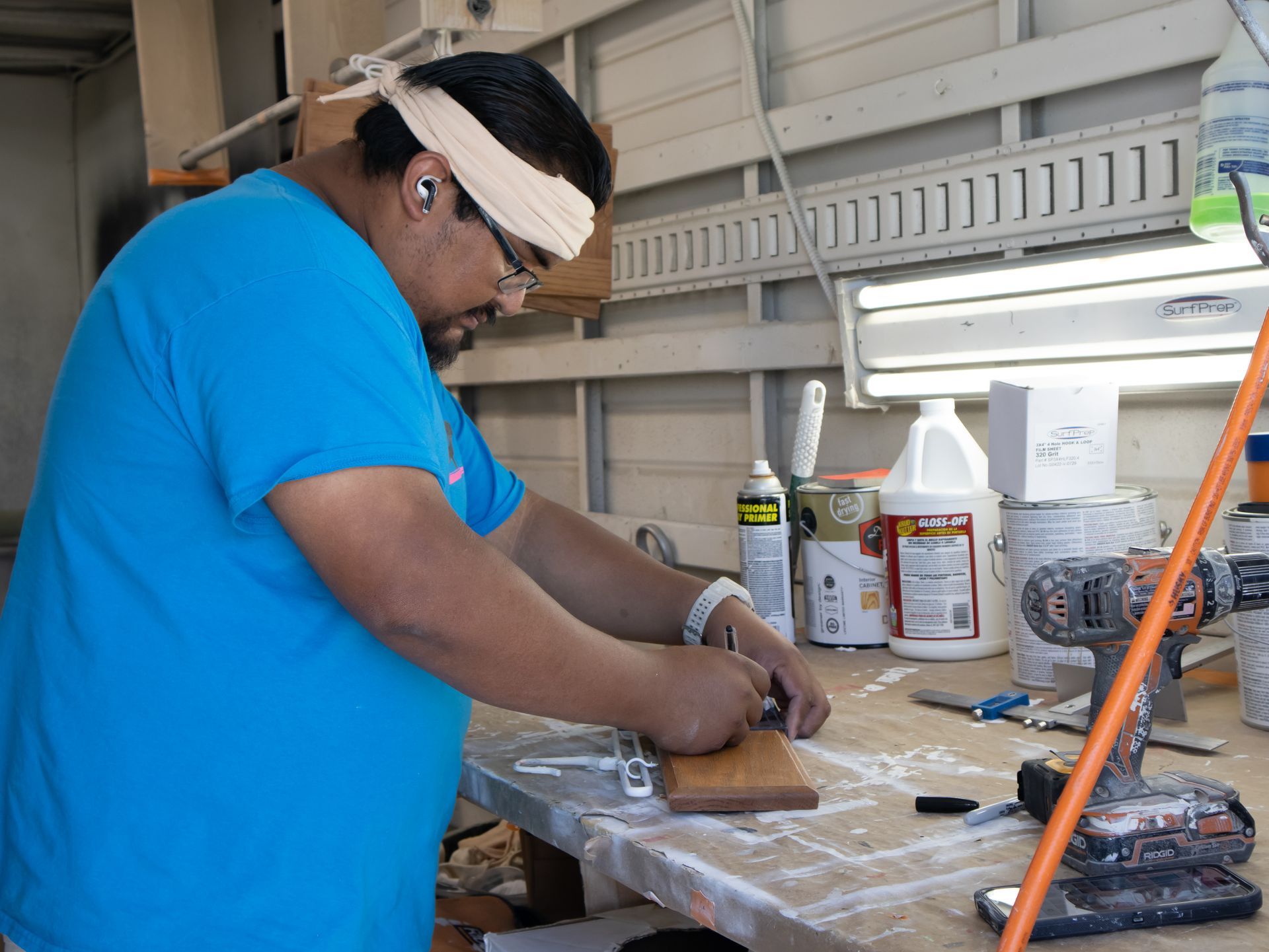 A man in a blue shirt is working on a piece of wood.