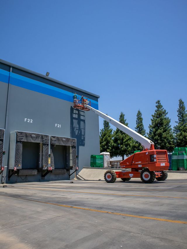 A red truck is parked in front of a large building.