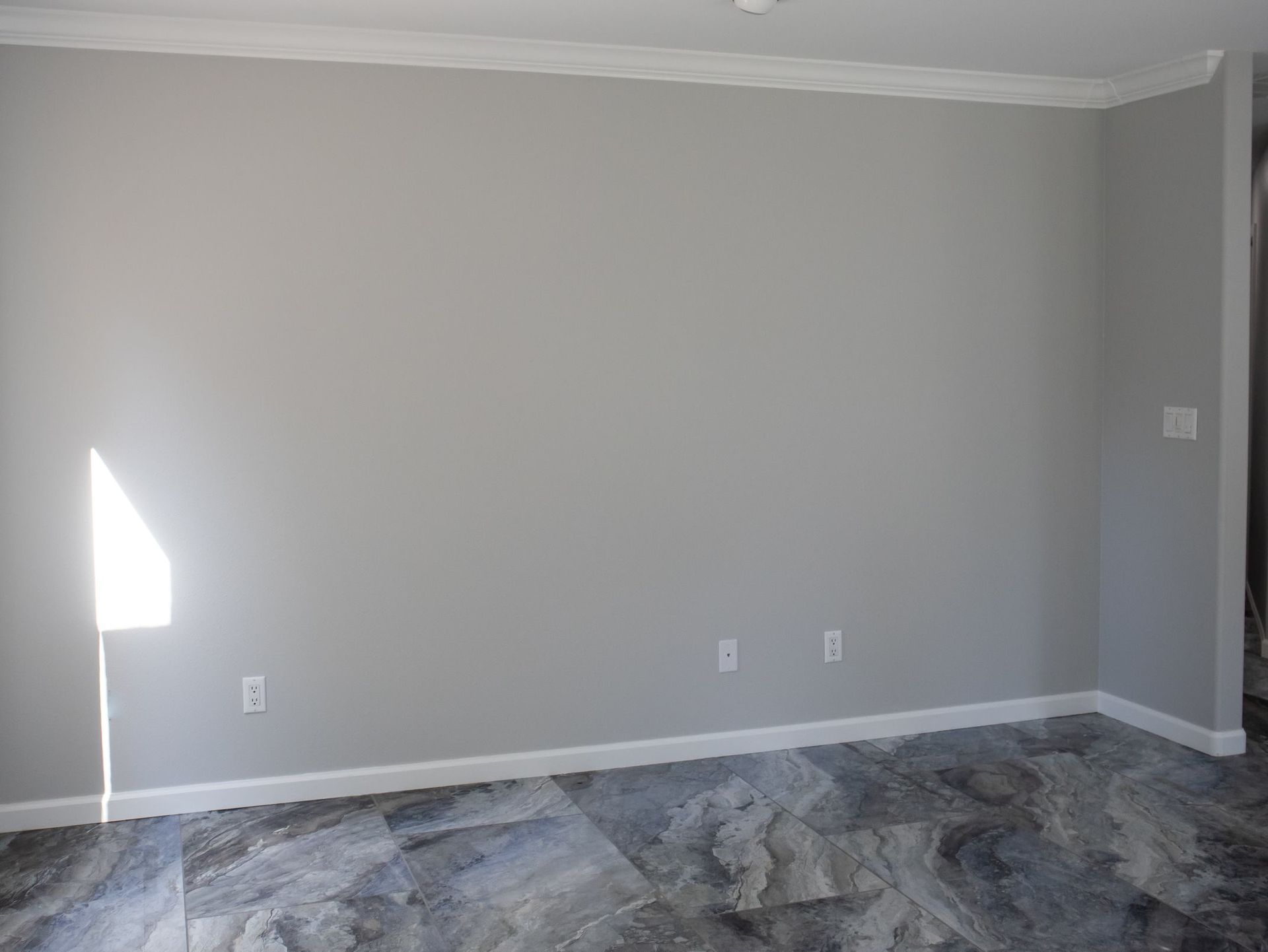 An empty room with gray walls and a tile floor.