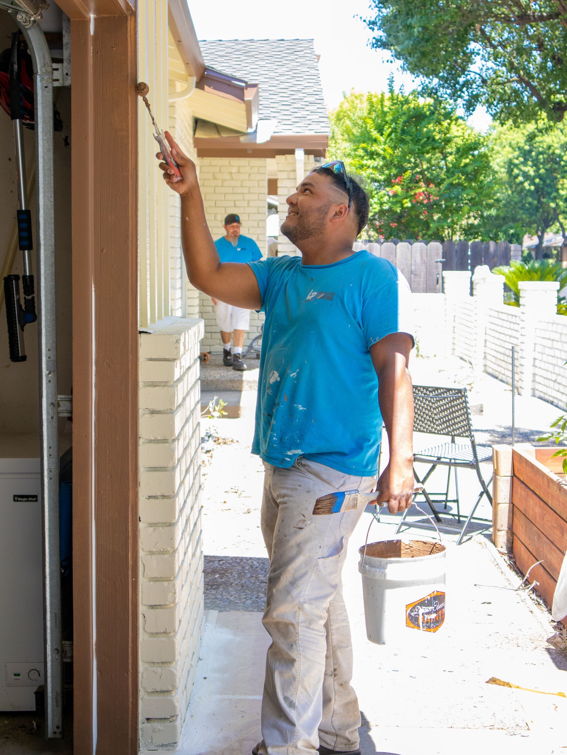 A man is painting the side of a house with a brush.