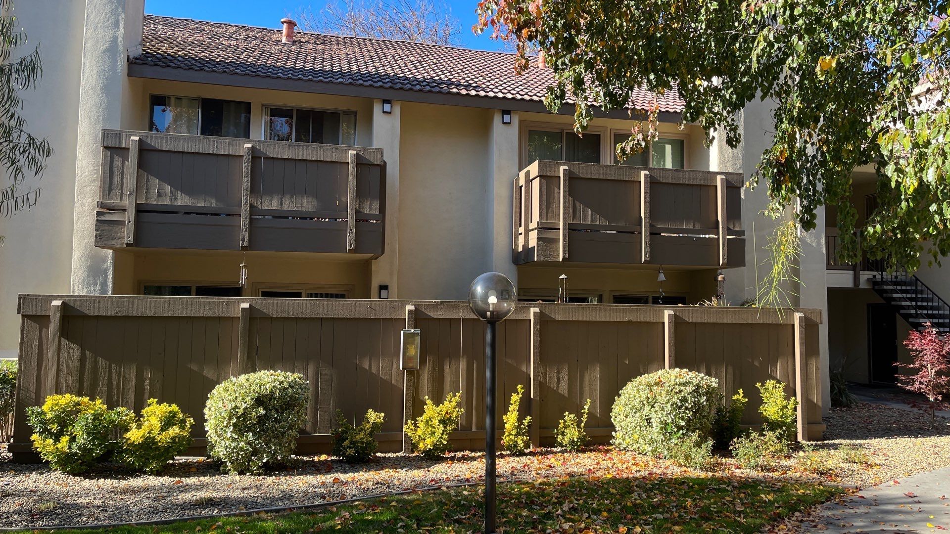 A building with a fence around it and a tree in front of it.