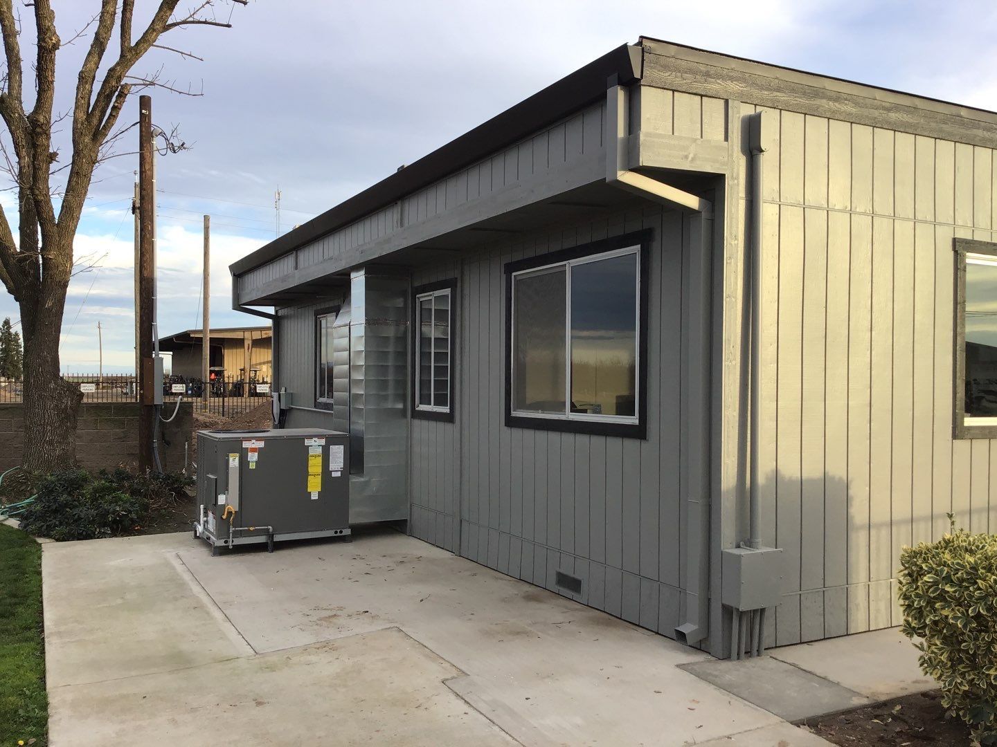 A small building with a lot of windows and a concrete walkway