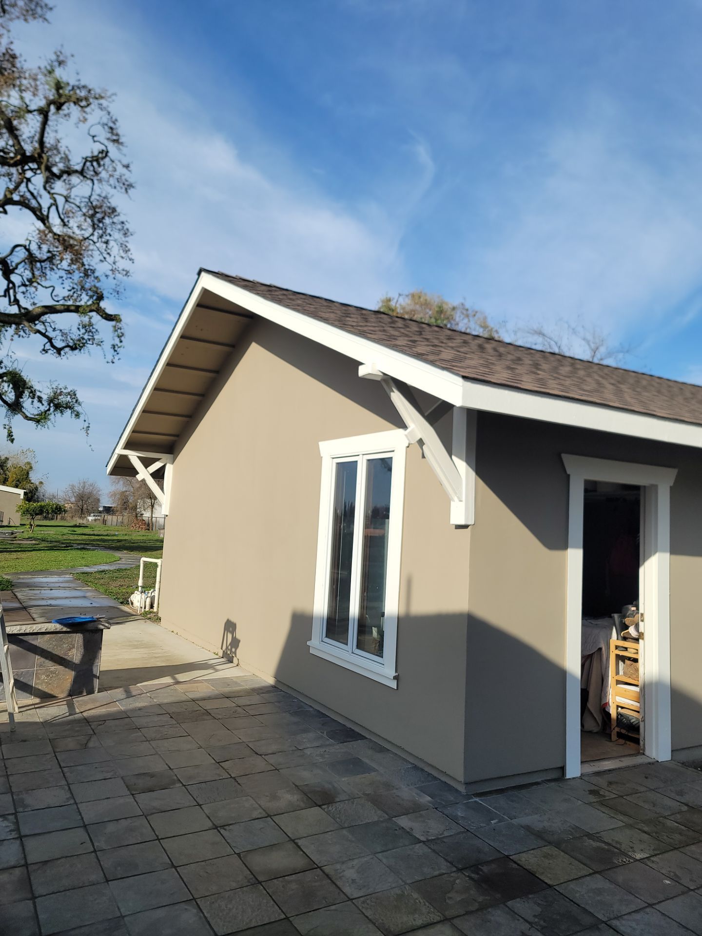 A small house with a patio and a tree in the background