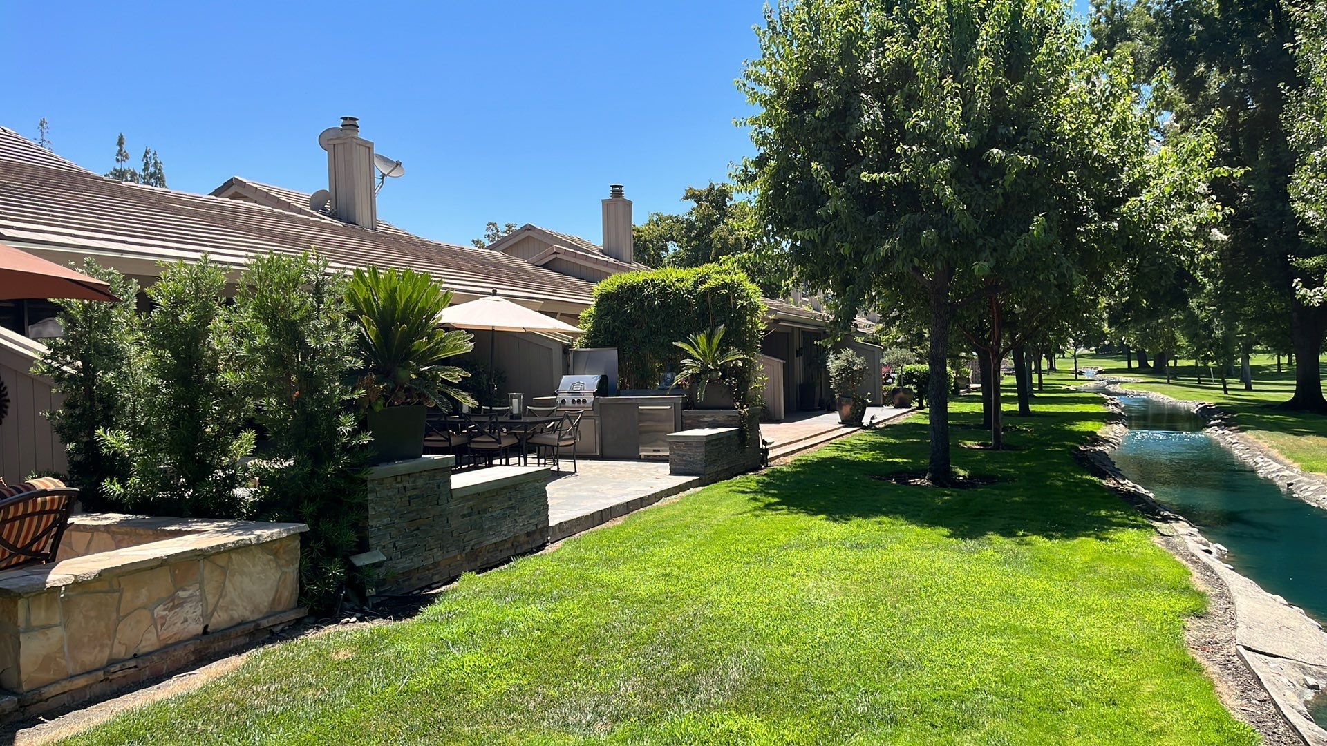 A lush green lawn with a house in the background