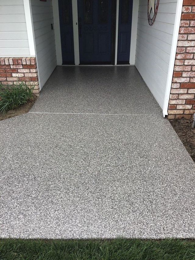 A concrete walkway leading to the front door of a house.