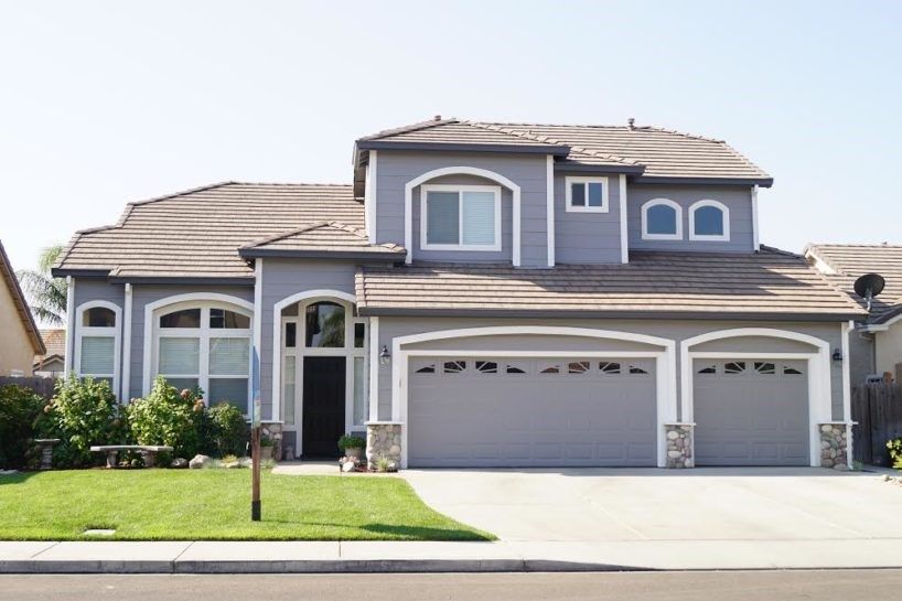 A large house with three garage doors and arched windows
