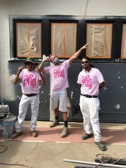 Lancaster Painting employees wearing pink shirts are standing in front of a building.