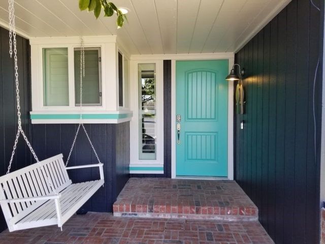 A porch with a swing and a blue door