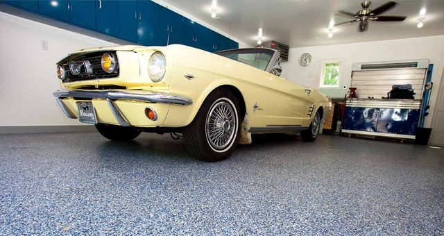 A yellow mustang convertible is parked in a garage.