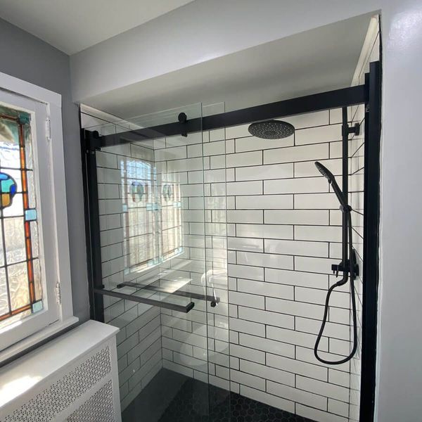 A shower with white tiles and a black shower head