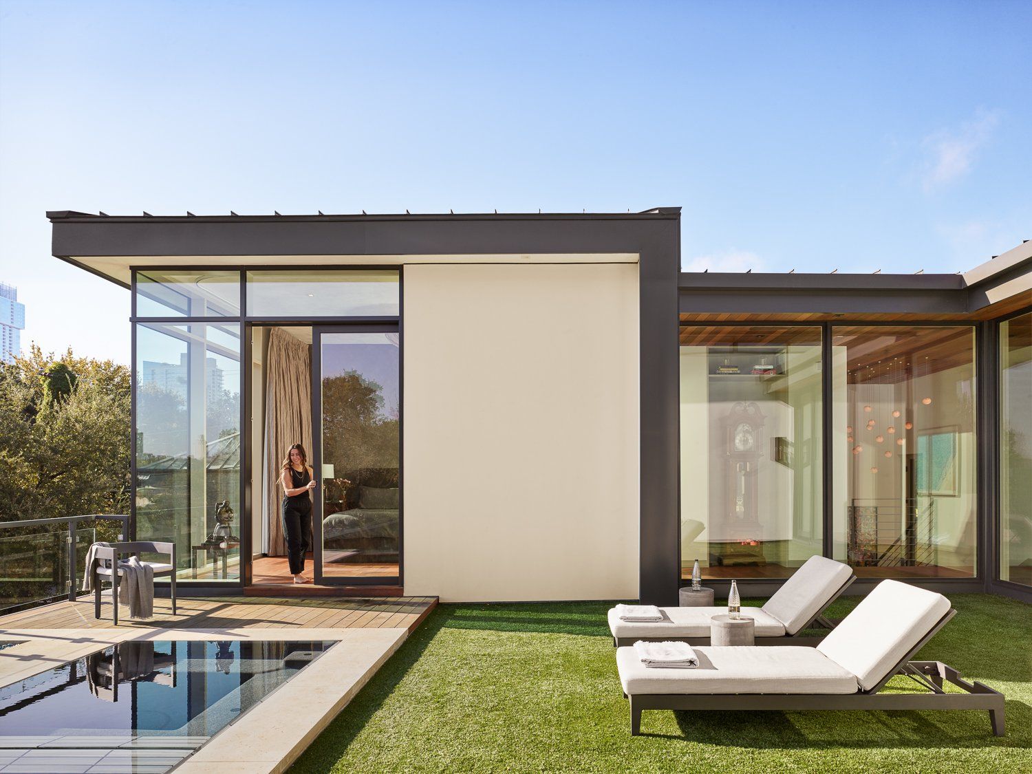 A woman stands in front of a house with a pool