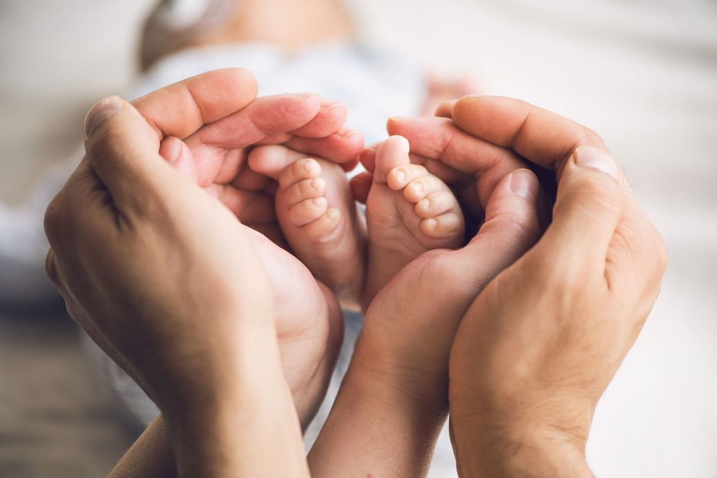 Una famiglia tiene in mano i piedini di un bambino.