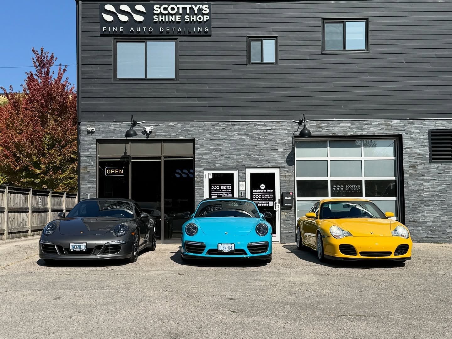 a Black, Blue, and yellow porsche 911 in front of scottys is london