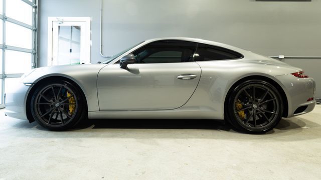 Silver sports coupe in a white garage, side view with black wheels and tinted windows