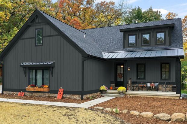Dark gray modern farmhouse with black trim, fall foliage in the background.