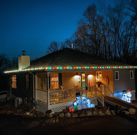 A house at night decorated with Christmas lights and inflatable snowmen.