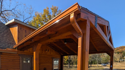 A wooden pavilion is sitting on top of a log cabin.