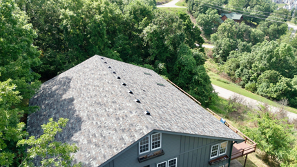 An aerial view of a house surrounded by trees and a road.