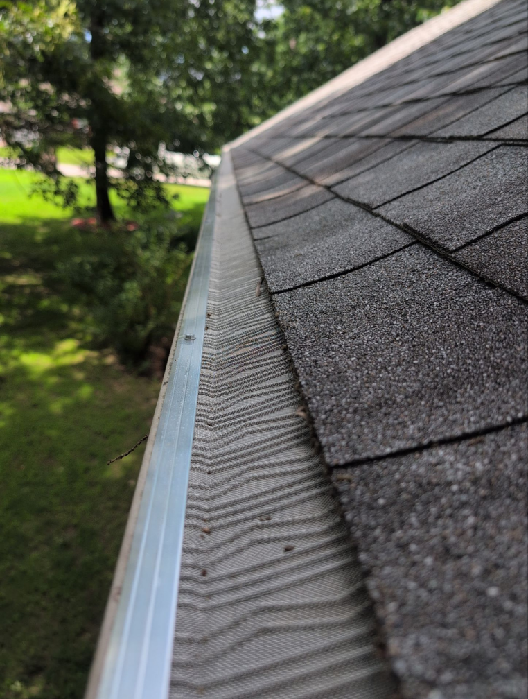 Close-up view of a roof edge showing a gutter with a mesh guard to prevent debris from entering.