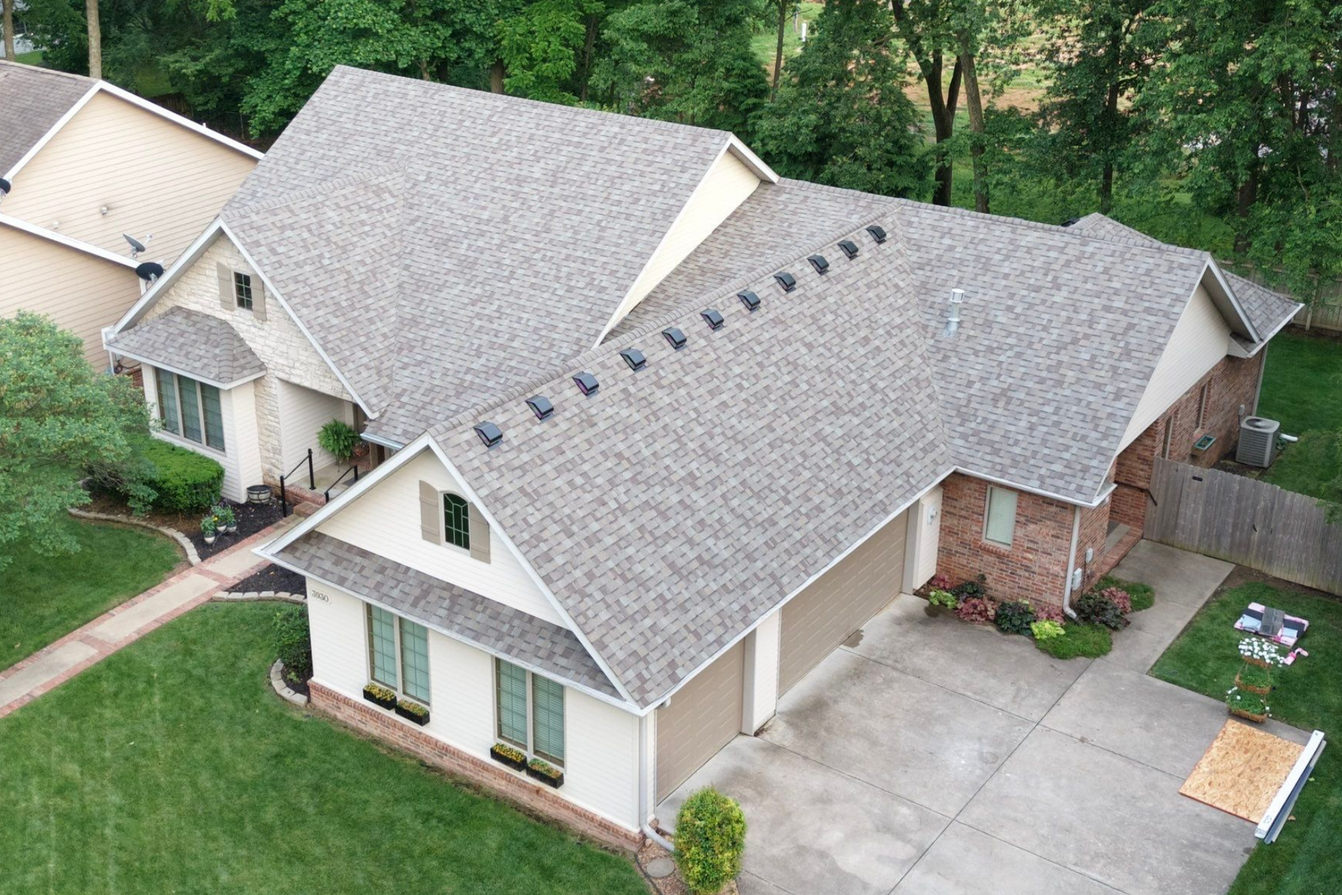 Suburban house with gray shingle roof, green lawn, and attached garage.