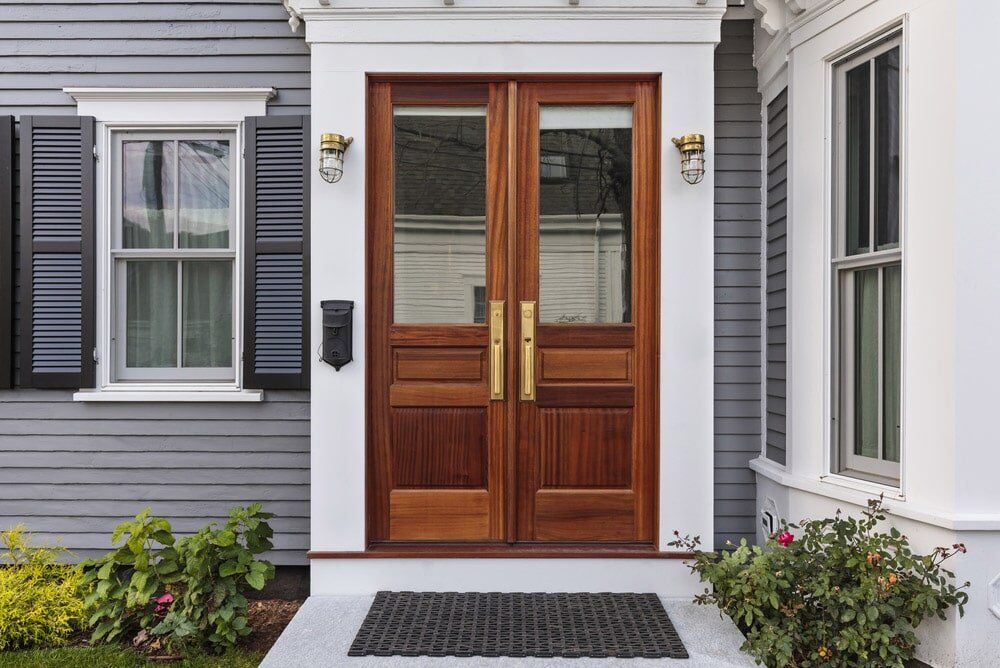 brown front door with gold trimming installed on a white house