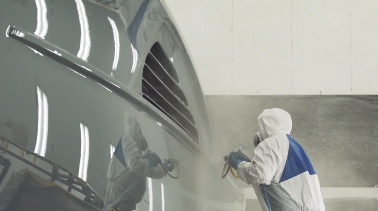 worker with actin sander coating boat