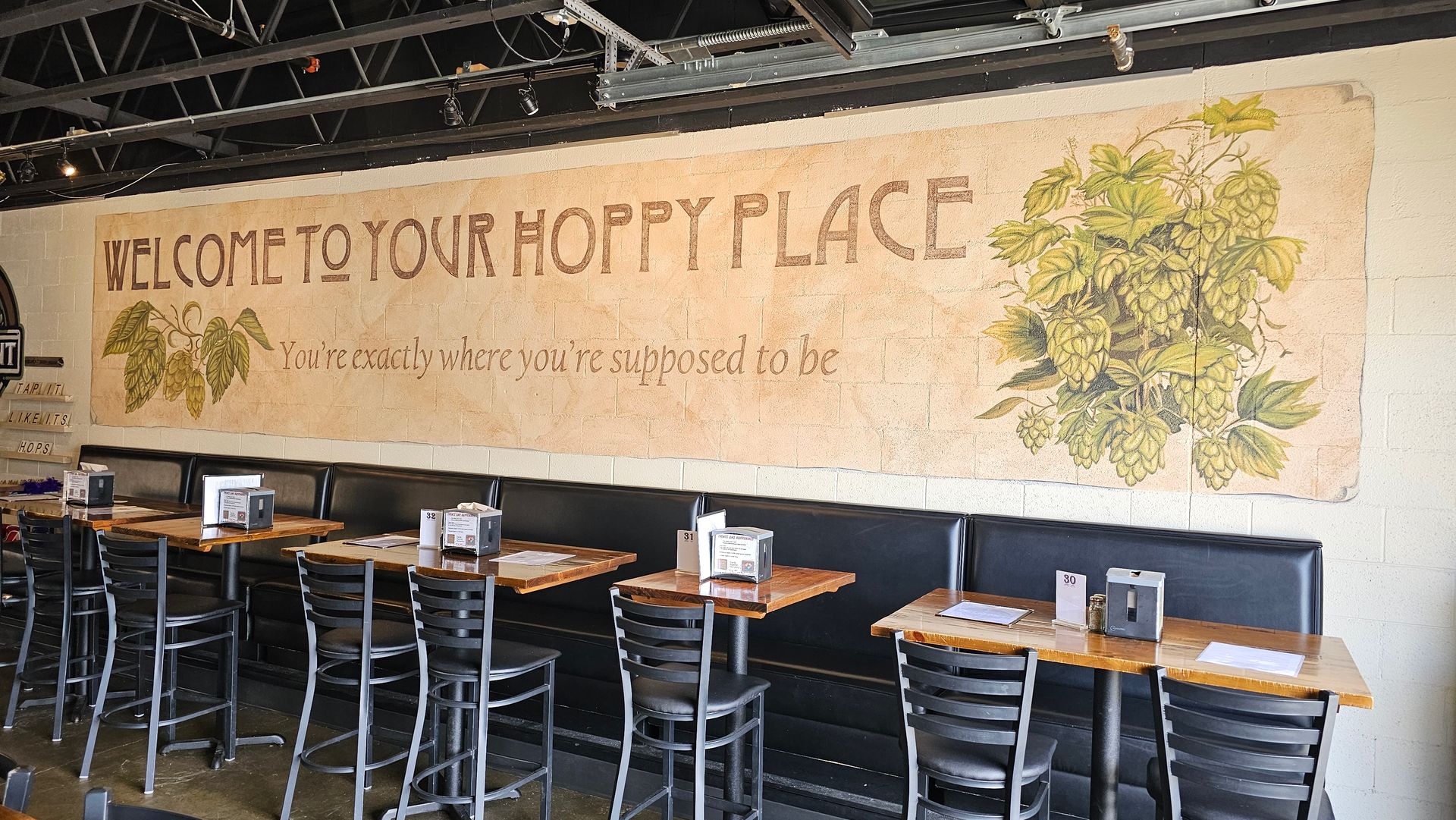 A restaurant with tables and chairs and a sign that says welcome to your hoppy place