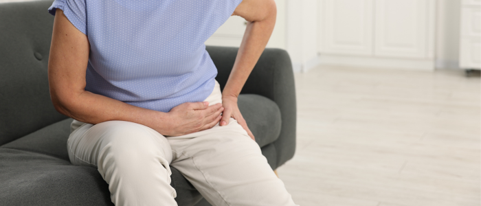 A woman is sitting on a couch holding her thigh in pain.