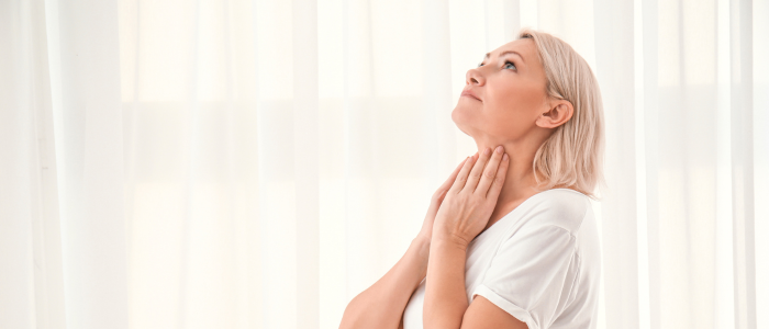 A woman is looking up at the sky while holding her neck.