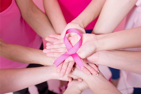 group of hands with pink cancer ribon