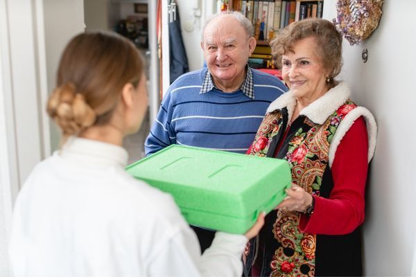 woman delivering food to elderly