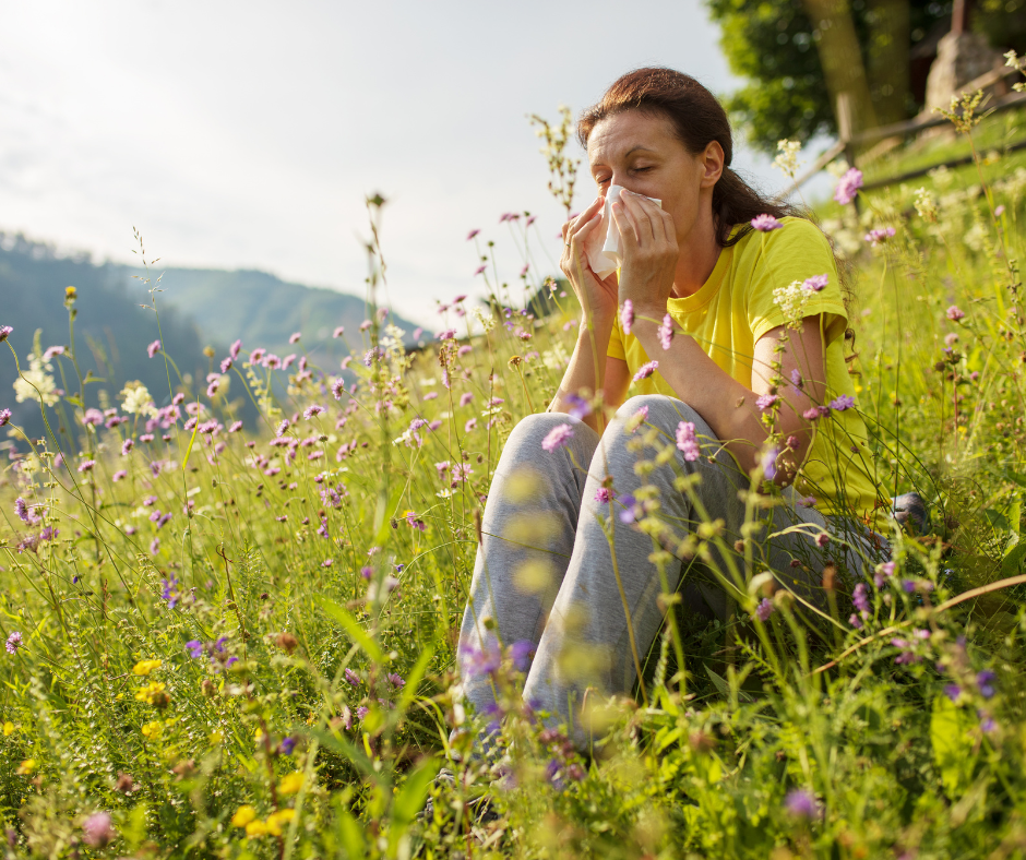 Woman sitting in field blowing her nose.