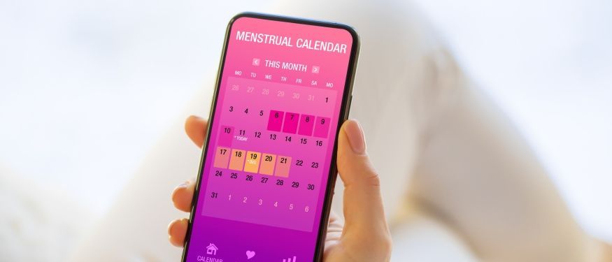 female hand holding mobile with menstral calendar app open