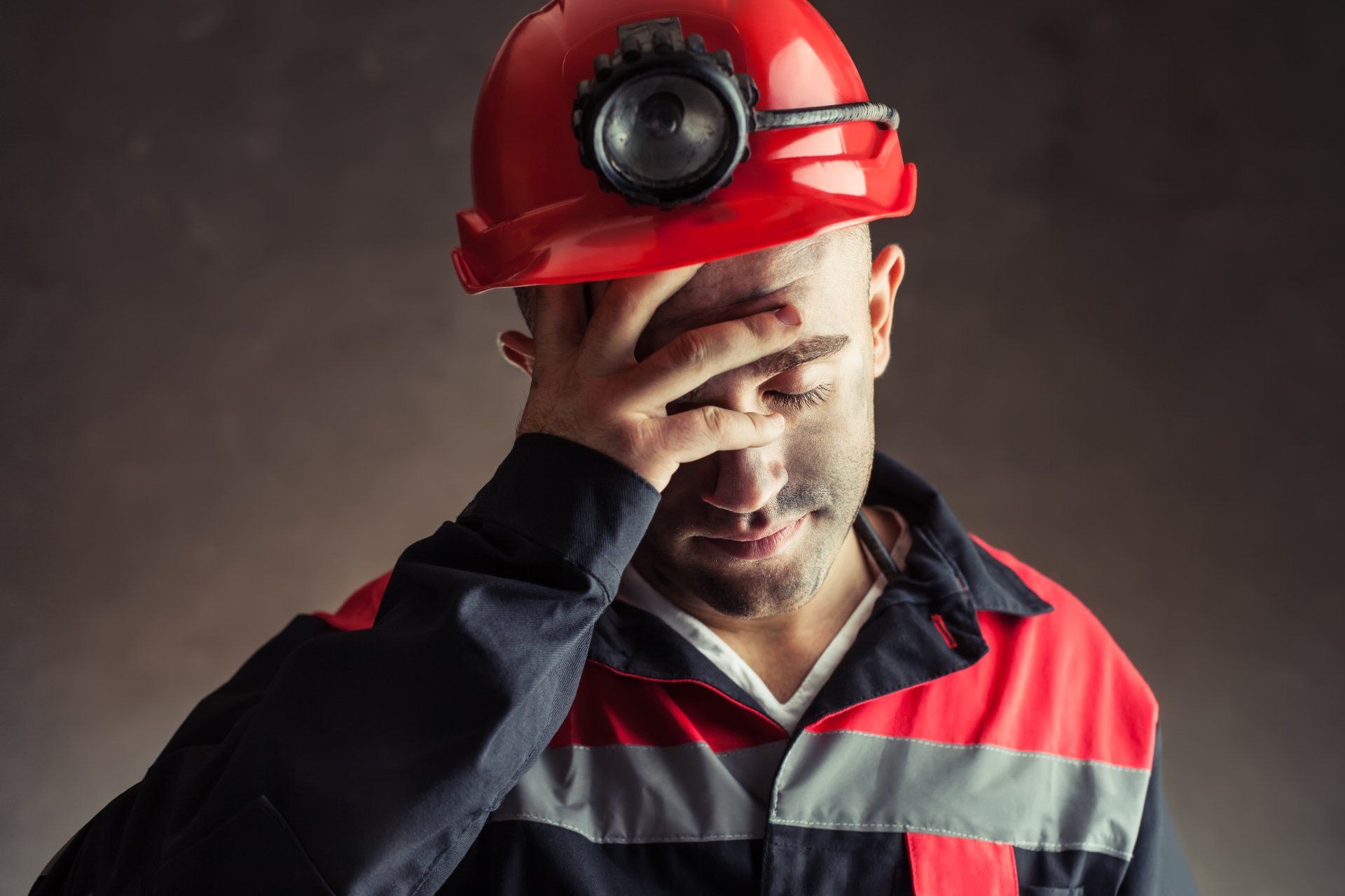 stressed male FIFO mine worker with hand over face