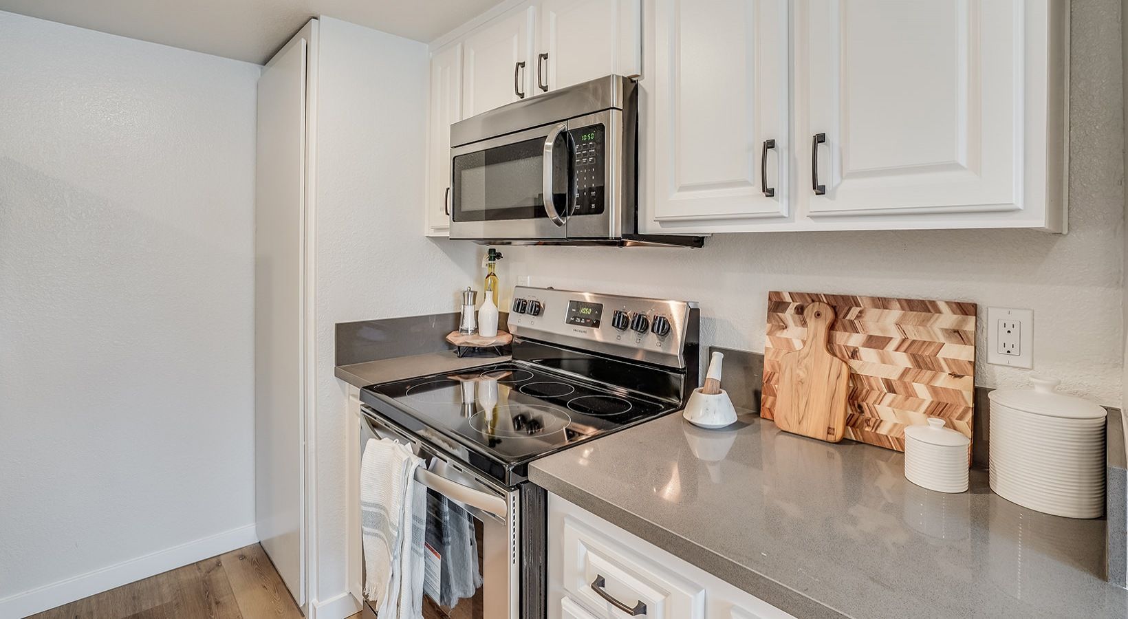 White kitchen with stainless steel appliances and gray countertops.