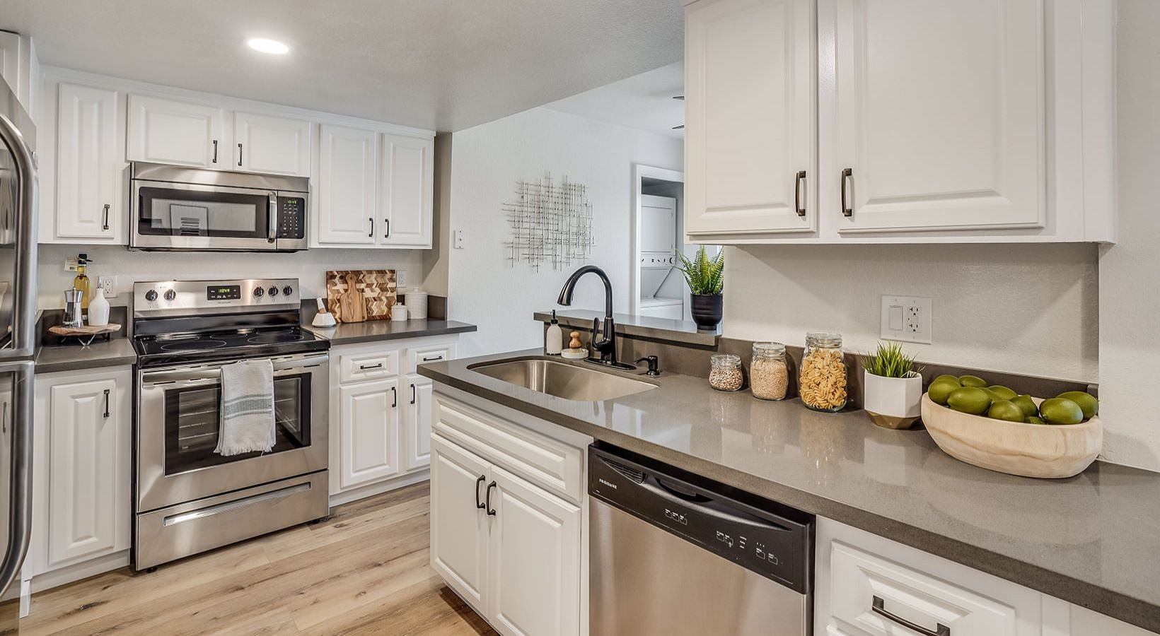Bright, modern kitchen with white cabinets, stainless steel appliances, and gray countertops.