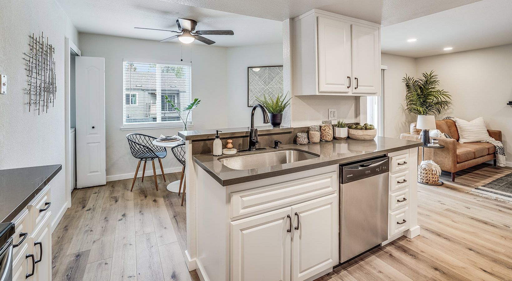 Modern kitchen with white cabinets, stainless steel appliances, and a breakfast bar.