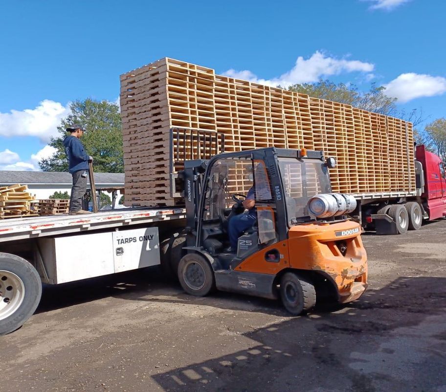 a forklift is loading wooden pallets onto a truck